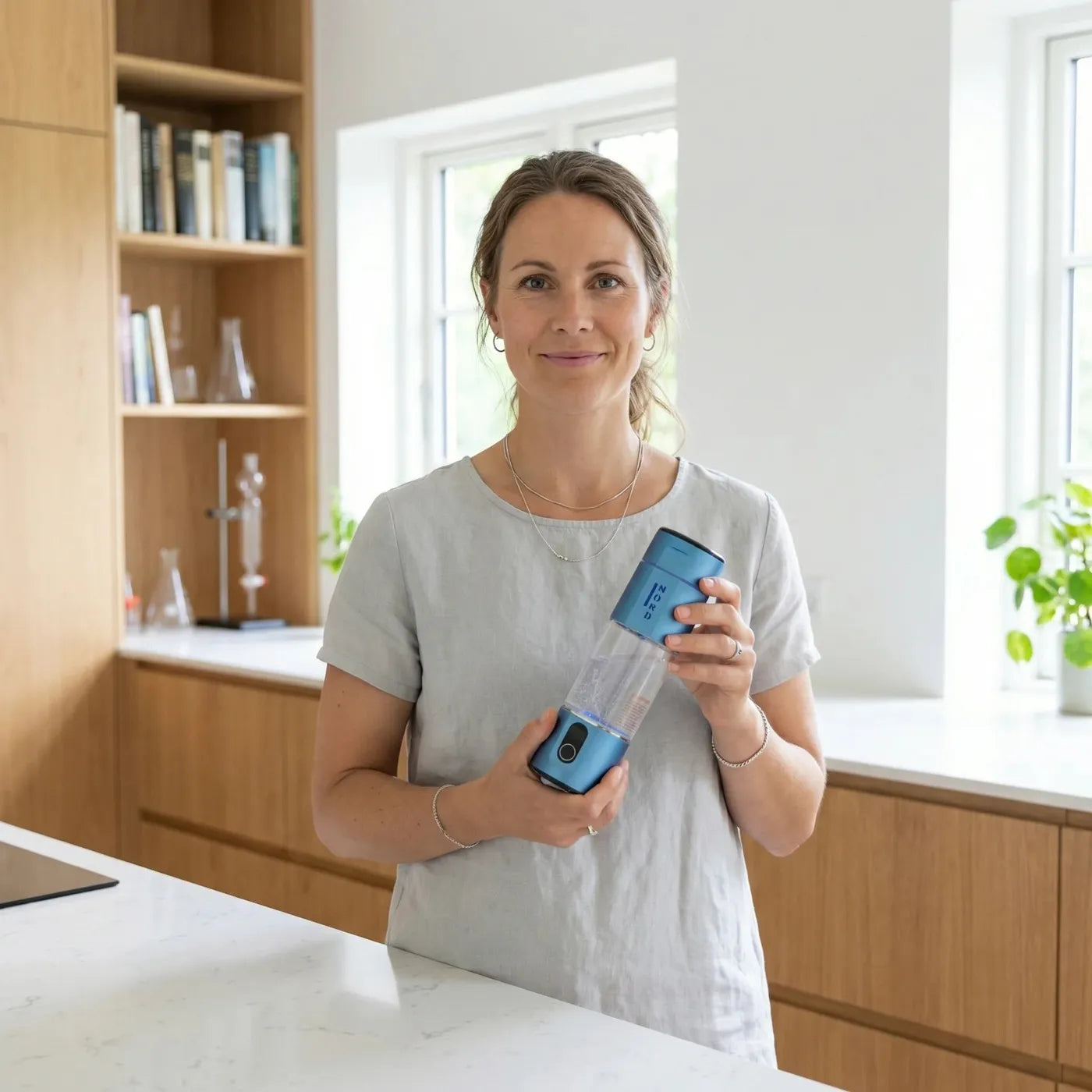 Donna in una cucina luminosa con in mano la Nord Hydrogen Bottle in Deep Space Blue